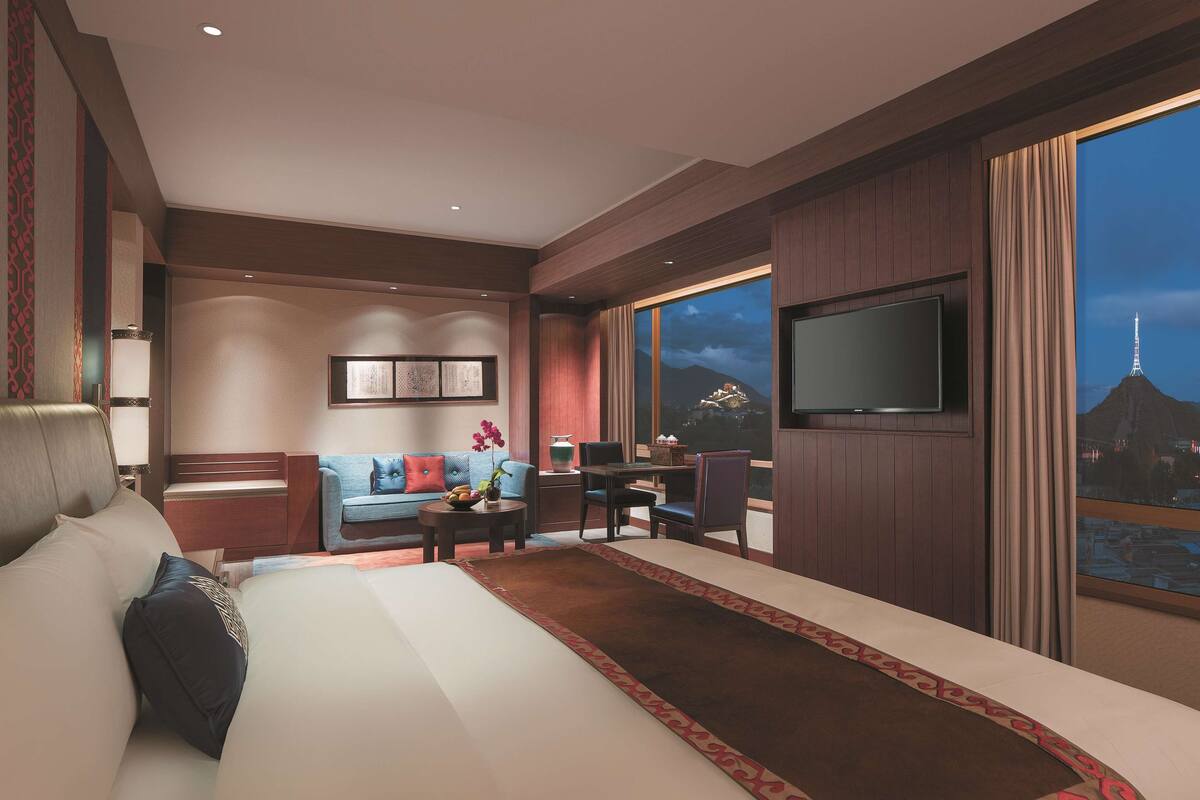 Una habitación de hotel moderna con una cama grande, un sofá, un escritorio y un televisor.