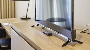 Un televisor de pantalla plana sobre un escritorio de madera en una habitación de hotel.