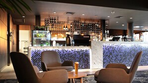 Zona de bar con asientos, una estantería para vinos y un refrigerador expositor.
