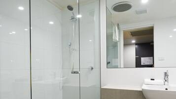 A modern bathroom with a glass-enclosed shower, a white sink, and a mirror above the sink.