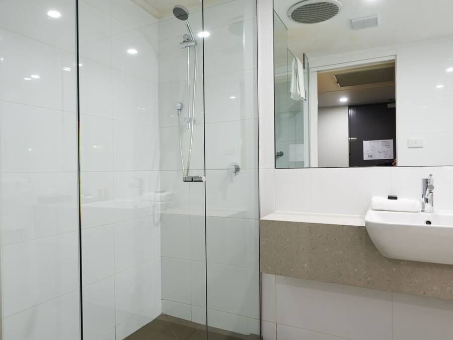 A modern bathroom with a glass-enclosed shower, a white sink, and a mirror above the sink.