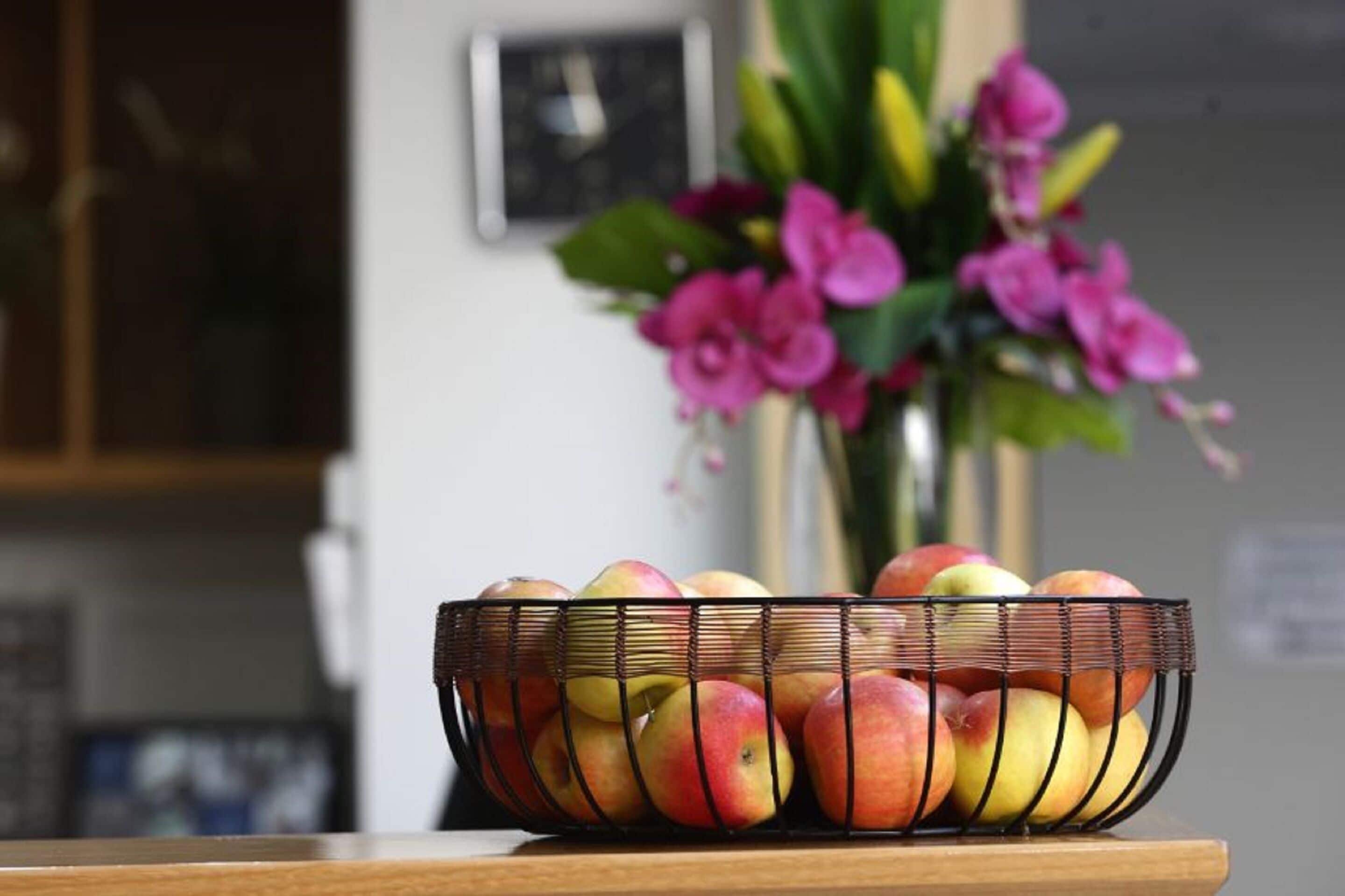 Una cesta de mimbre con manzanas sobre una mesa de madera.