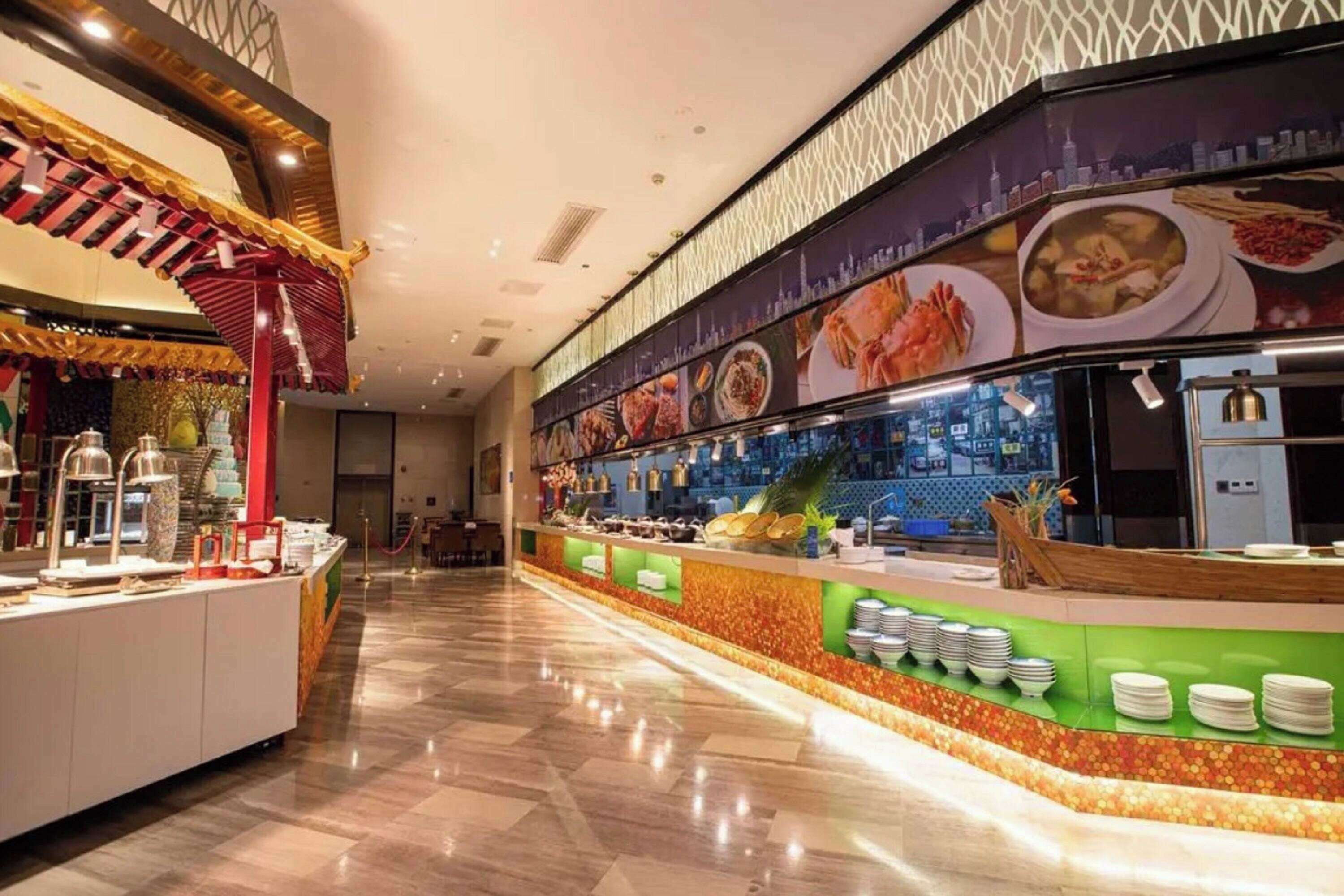 A buffet area with a variety of dishes displayed on the wall and a counter with plates and utensils.