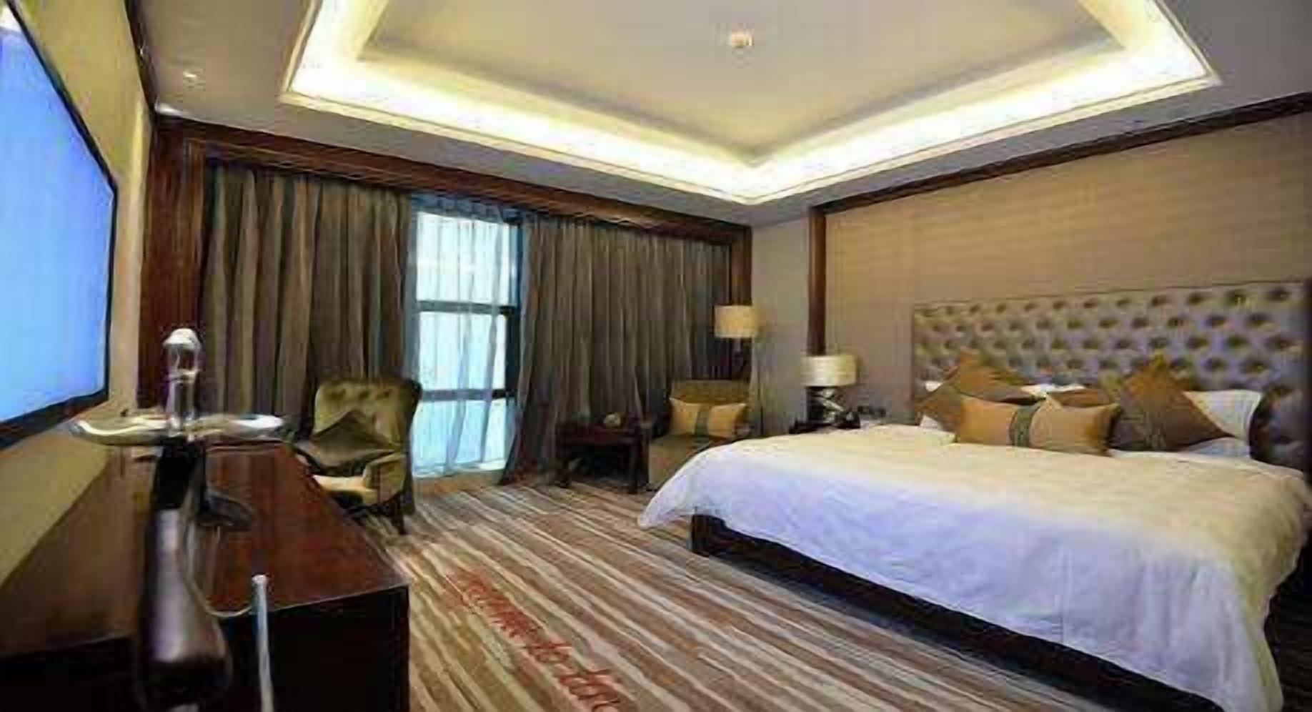 Una habitación de hotel con una cama grande, un escritorio, una silla y un televisor.