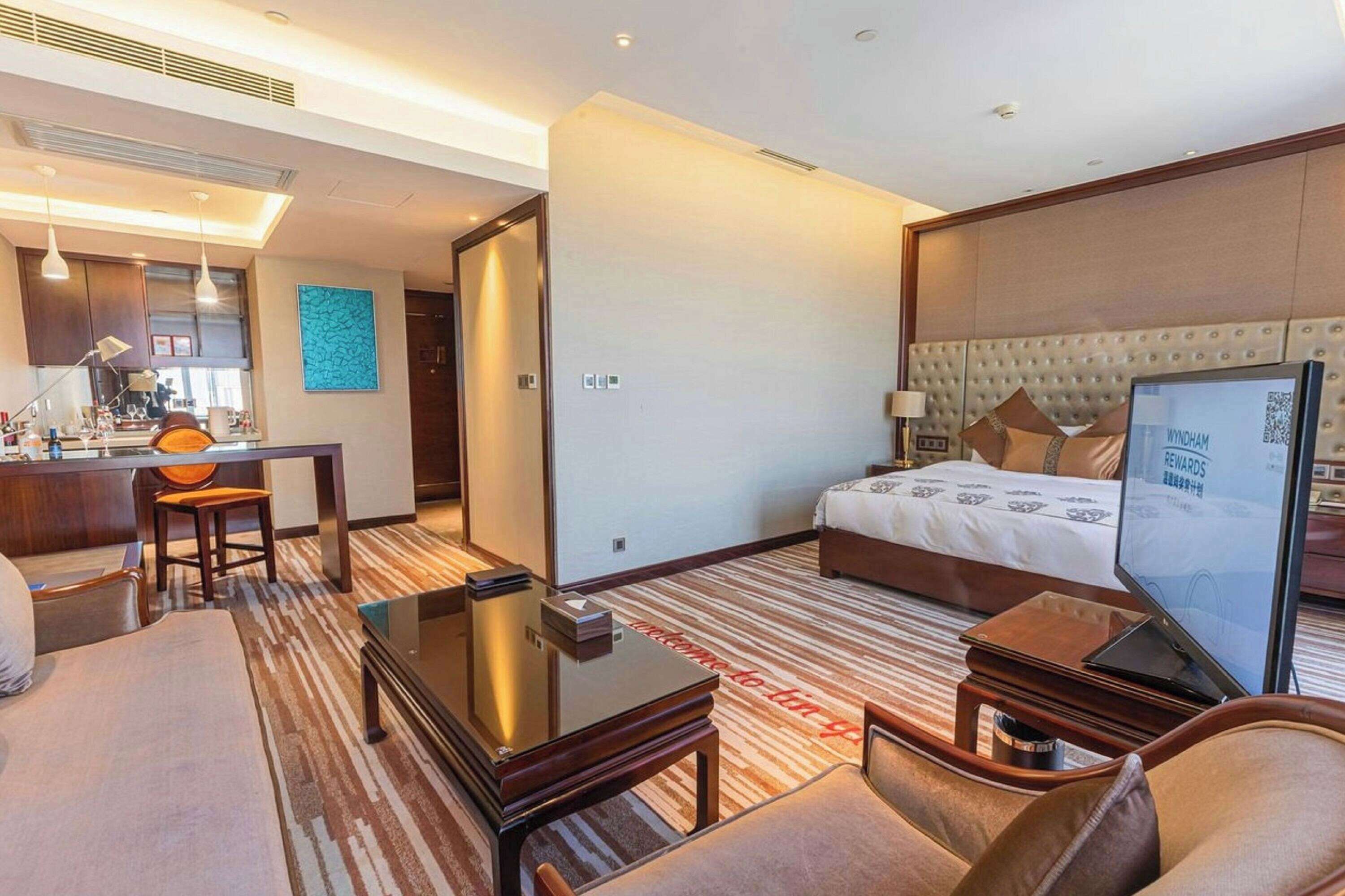 Une chambre d’hôtel équipée d’un lit, d’un bureau, d’une chaise, d’une télévision et d’un mini-bar.