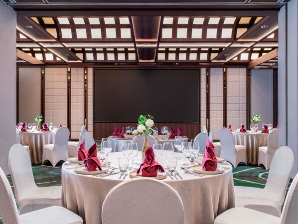A banquet hall with round tables, white chairs, and a large screen at the front. - Mercure Jakarta Sabang (Jakarta)