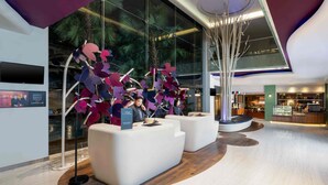 A modern lobby with a reception desk, seating area, and a decorative installation. - Mercure Jakarta Sabang (Jakarta)