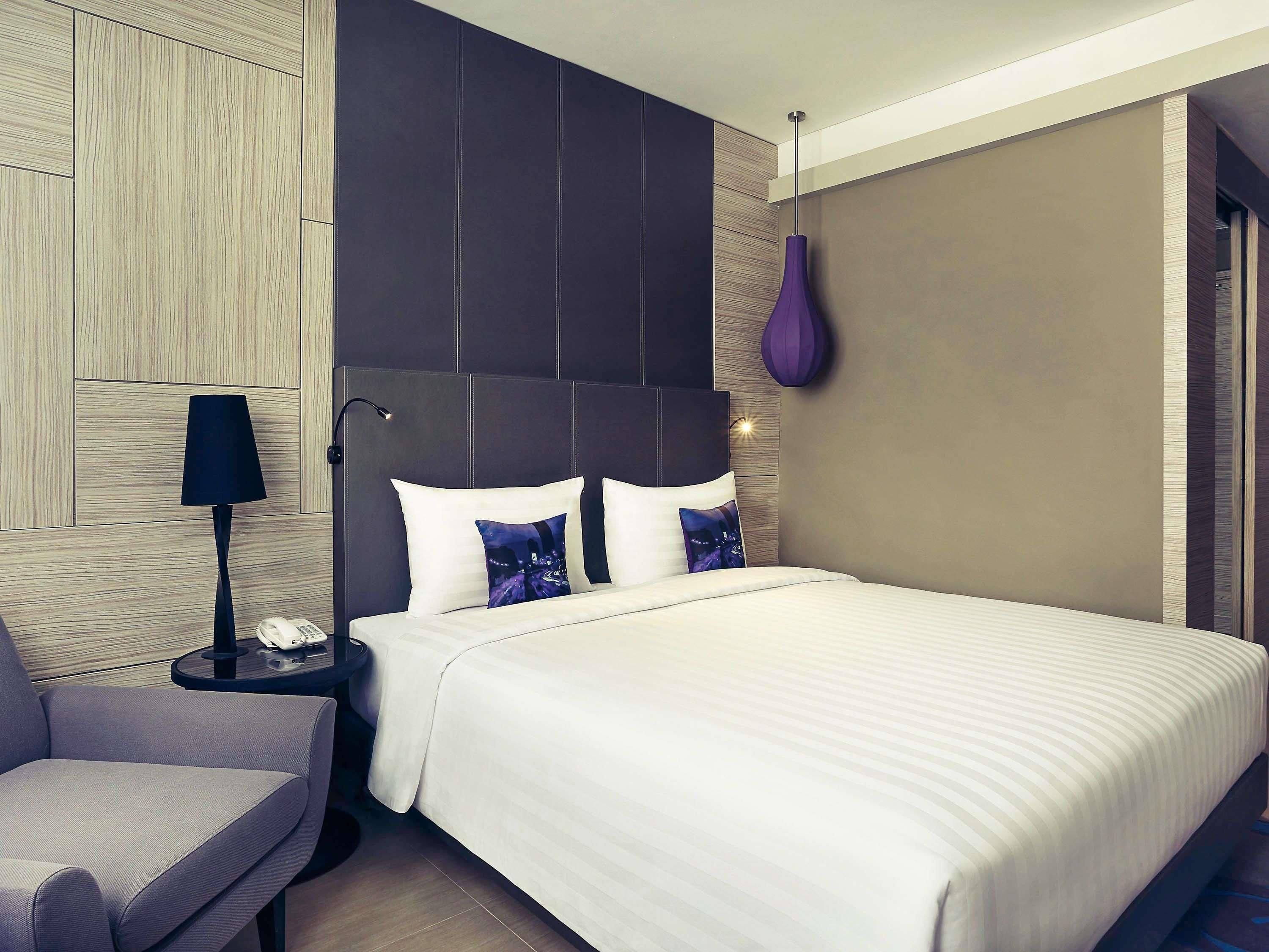 Een moderne hotelkamer met een groot bed, een nachtkastje met een lamp en een stoel.