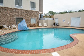 A swimming pool with lounge chairs and a covered area, a no diving sign, and a lifebuoy on the wall.