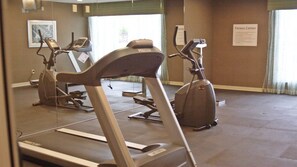A fitness center with treadmills, stationary bikes, and a mirrored wall.