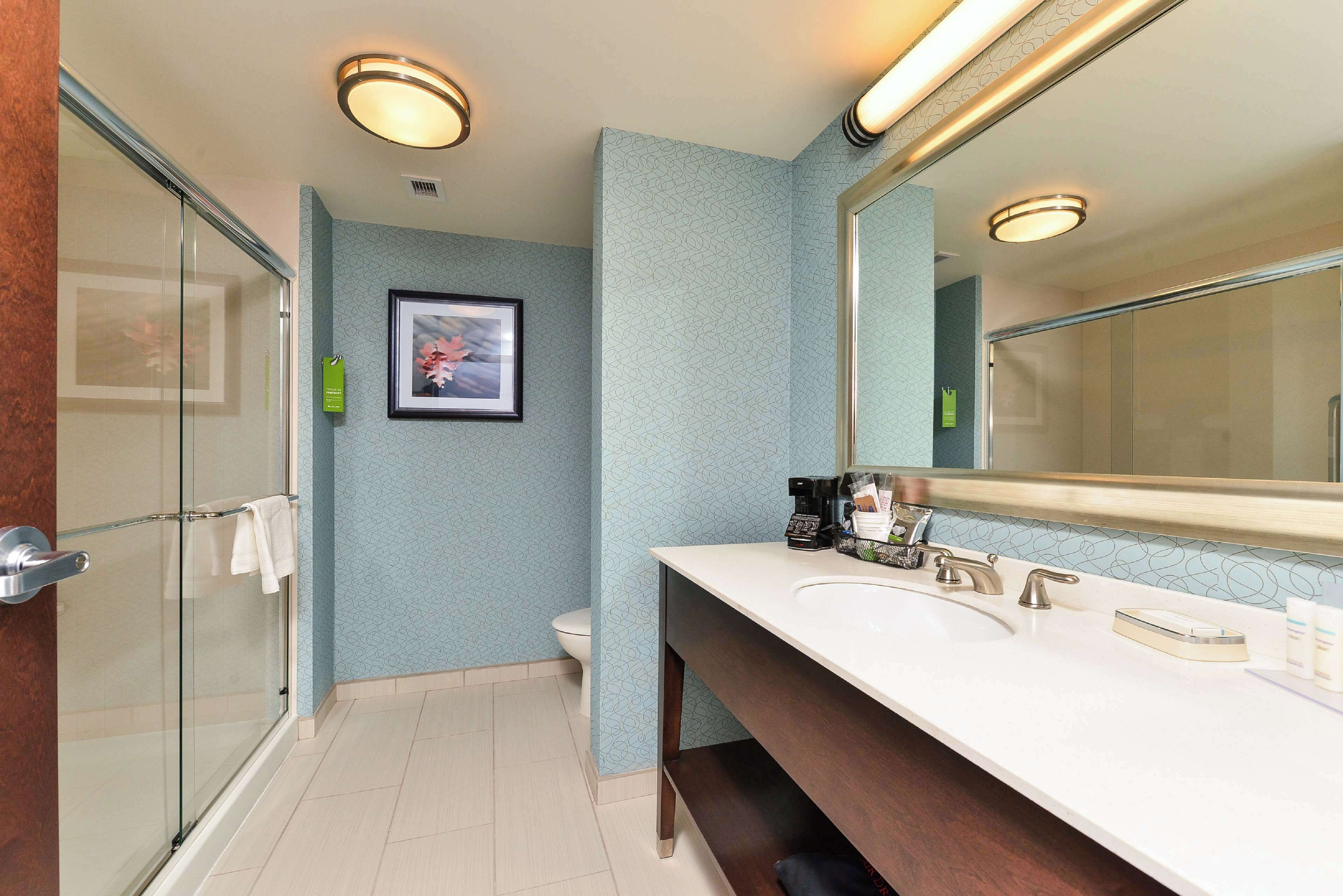 A modern bathroom with a glass shower enclosure, a white sink with a large mirror, and a toilet.