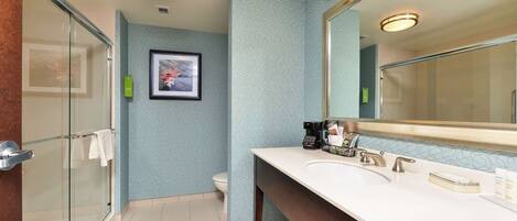 A modern bathroom with a glass shower enclosure, a white sink with a large mirror, and a toilet.