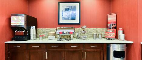 A kitchen area with a coffee machine, a microwave, and a trash can.