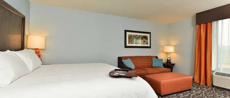 Une chambre d’hôtel avec un grand lit, un canapé, une petite table et un tableau au mur.