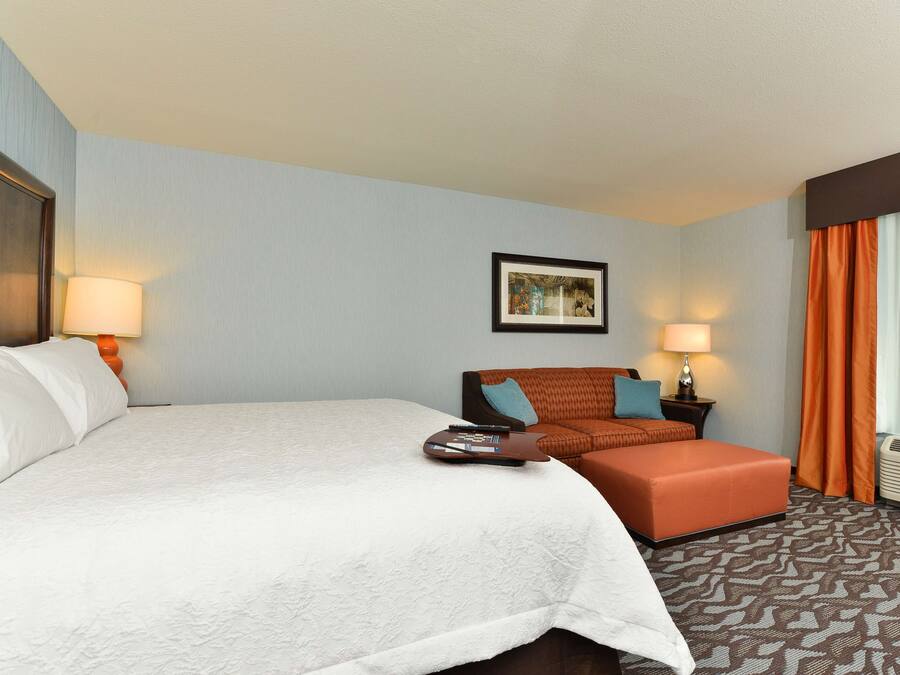 Quarto de hotel com uma cama grande, um sofá, uma mesinha e um quadro na parede.