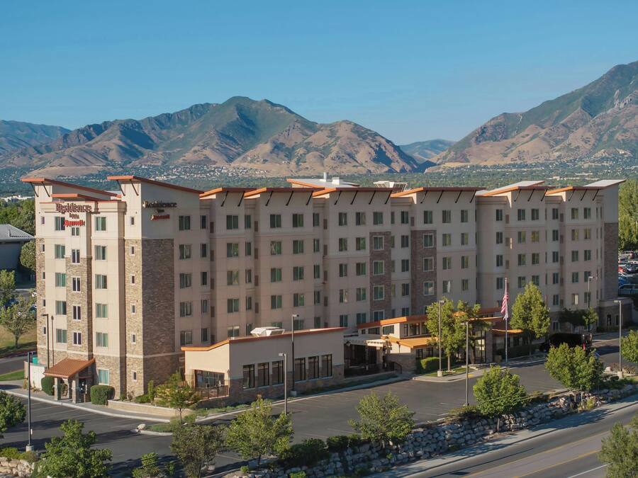 A multi-story hotel with a central courtyard, surrounded by mountains.