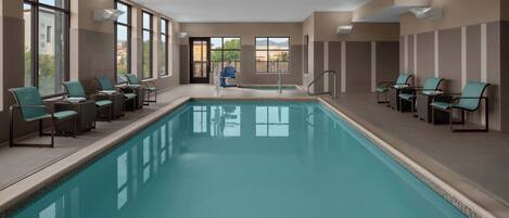 A swimming pool with lounge chairs and a door leading outside.