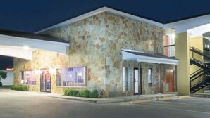 A stone building with a flat roof, a staircase, and a parking lot. - Super 8 by Wyndham San Antonio Near Fort Sam Houston (San Antonio)