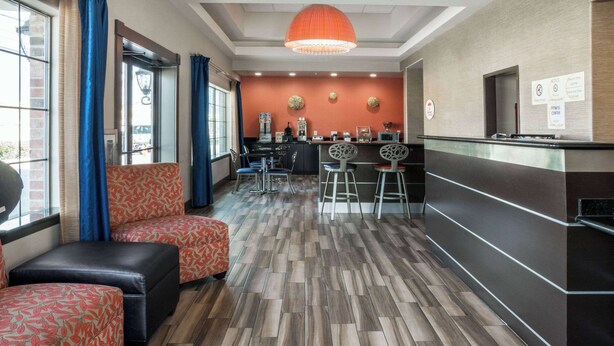 A hotel lobby with a reception desk, seating area, and a herringbone-patterned floor. - Super 8 by Wyndham San Antonio Near Fort Sam Houston (San Antonio)