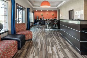 Un vestíbulo de hotel con recepción, zona de estar y suelo con motivo de espiga.