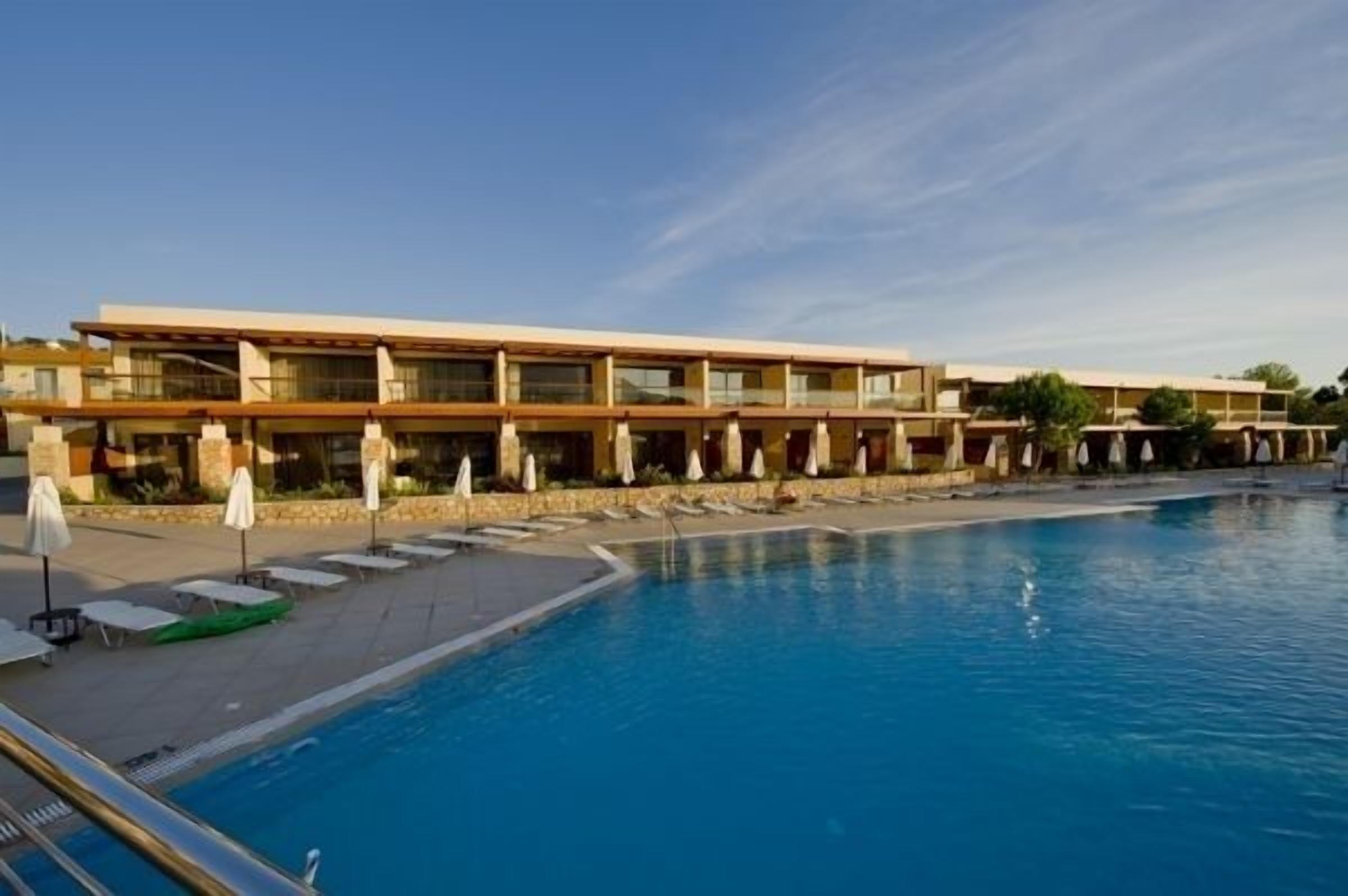 A hotel with a swimming pool, multiple balconies, and sun loungers.
