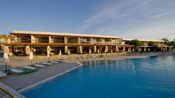 A hotel with a swimming pool, multiple balconies, and sun loungers.