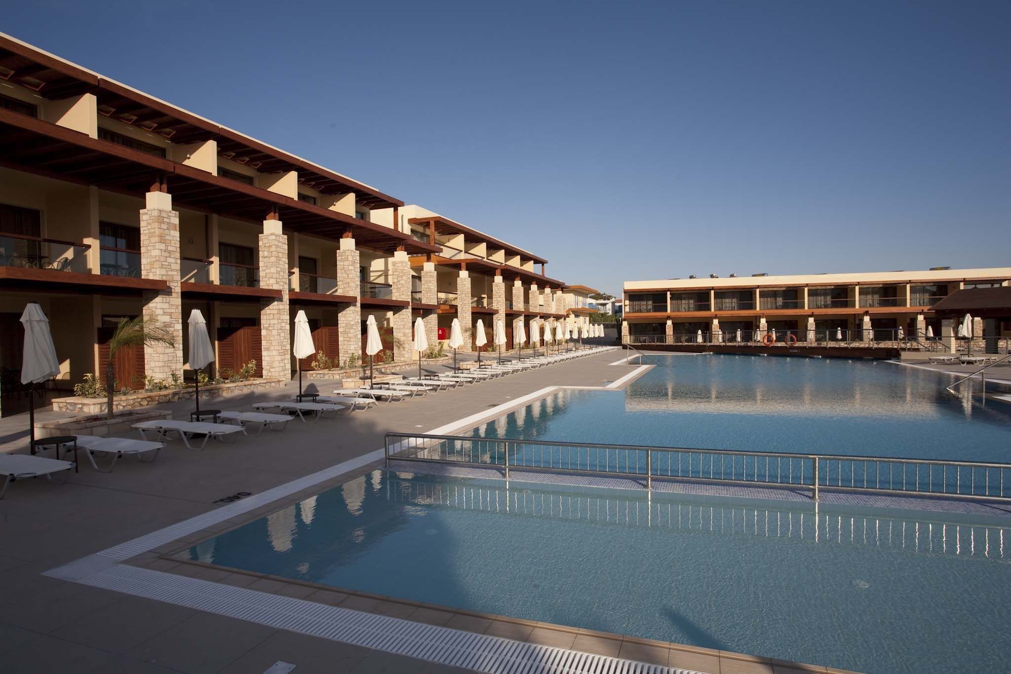 A hotel with a large pool, multiple balconies, and sun loungers.