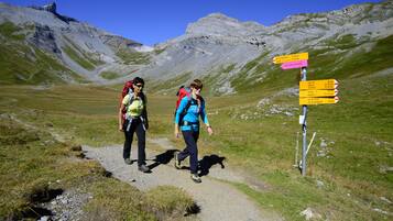 Two hikers on a mountain trail with a directional signpost.