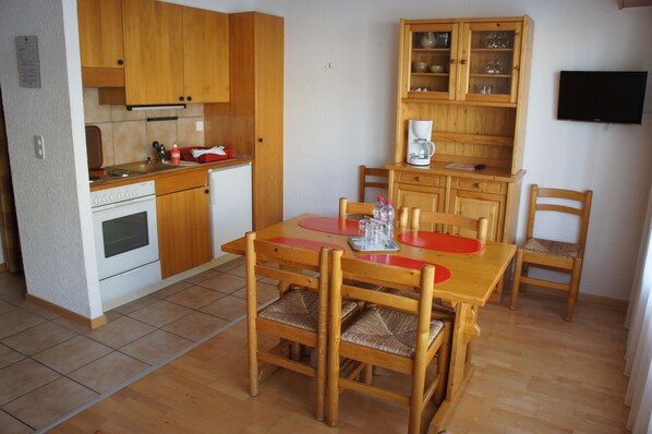 Una cocina compacta con armarios de madera, horno empotrado y cafetera.