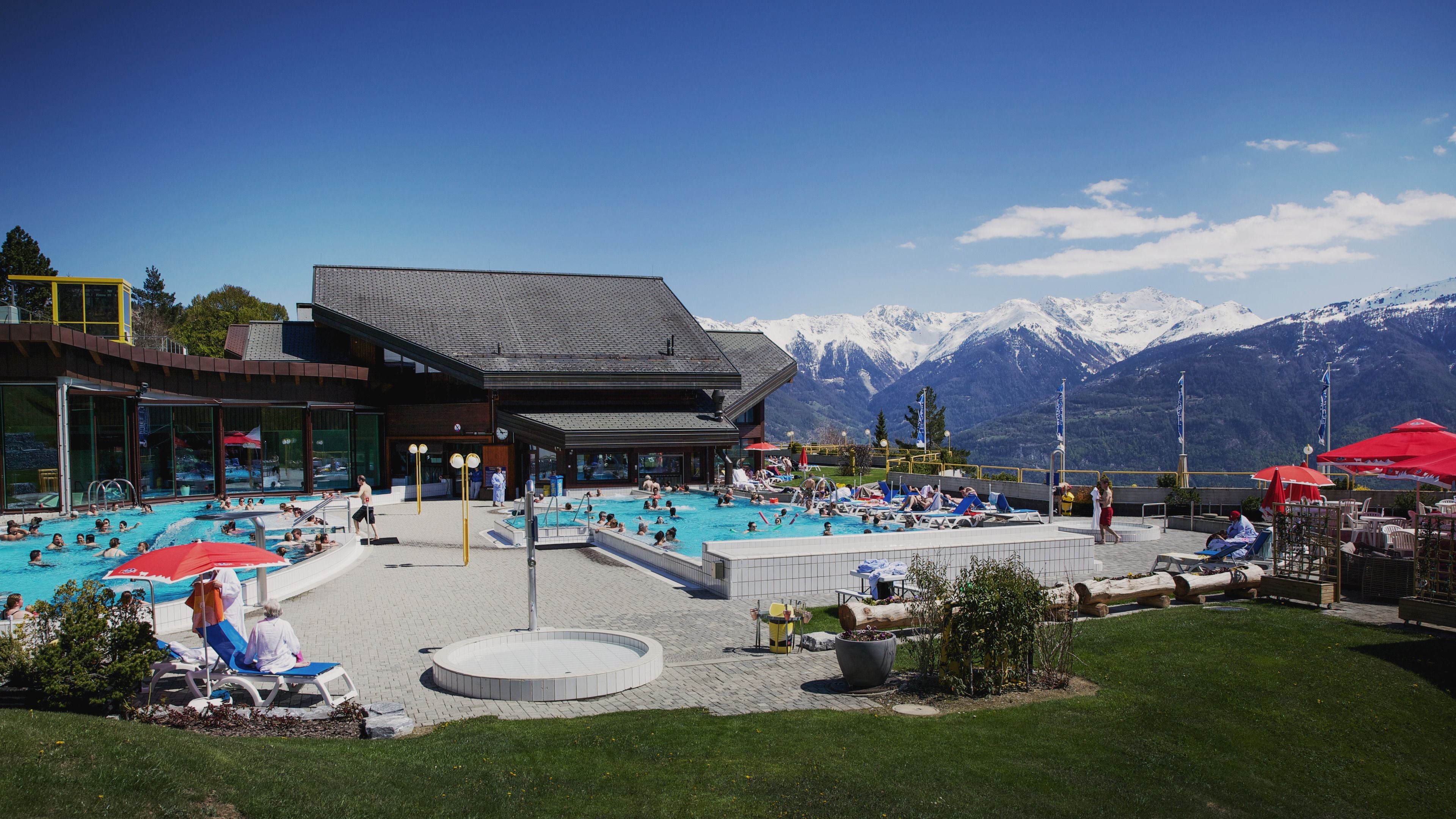 Un espace piscine comprenant plusieurs piscines, des chaises longues et des parasols.
