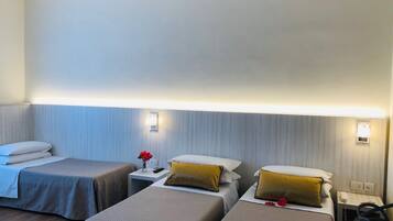 Una habitación de hotel con dos camas individuales, una mesita de noche con lámpara y una silla.