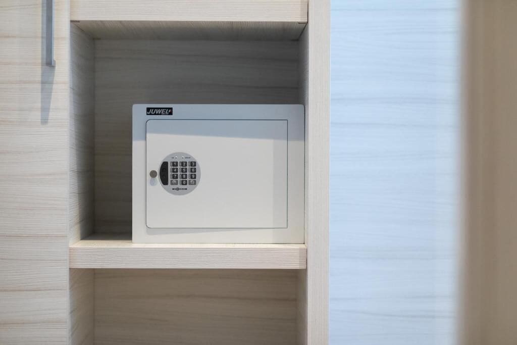 A secure safe with a keypad lock, placed in a wooden cabinet.