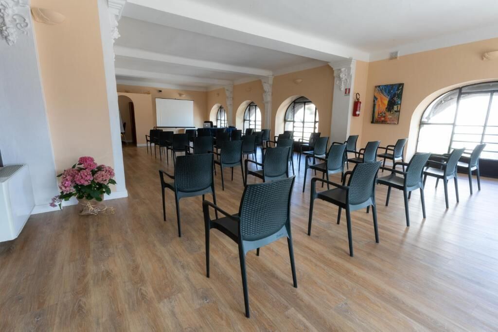 A conference room with rows of chairs, a whiteboard, and a large window.