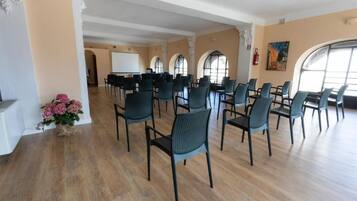 A conference room with rows of chairs, a whiteboard, and a large window.