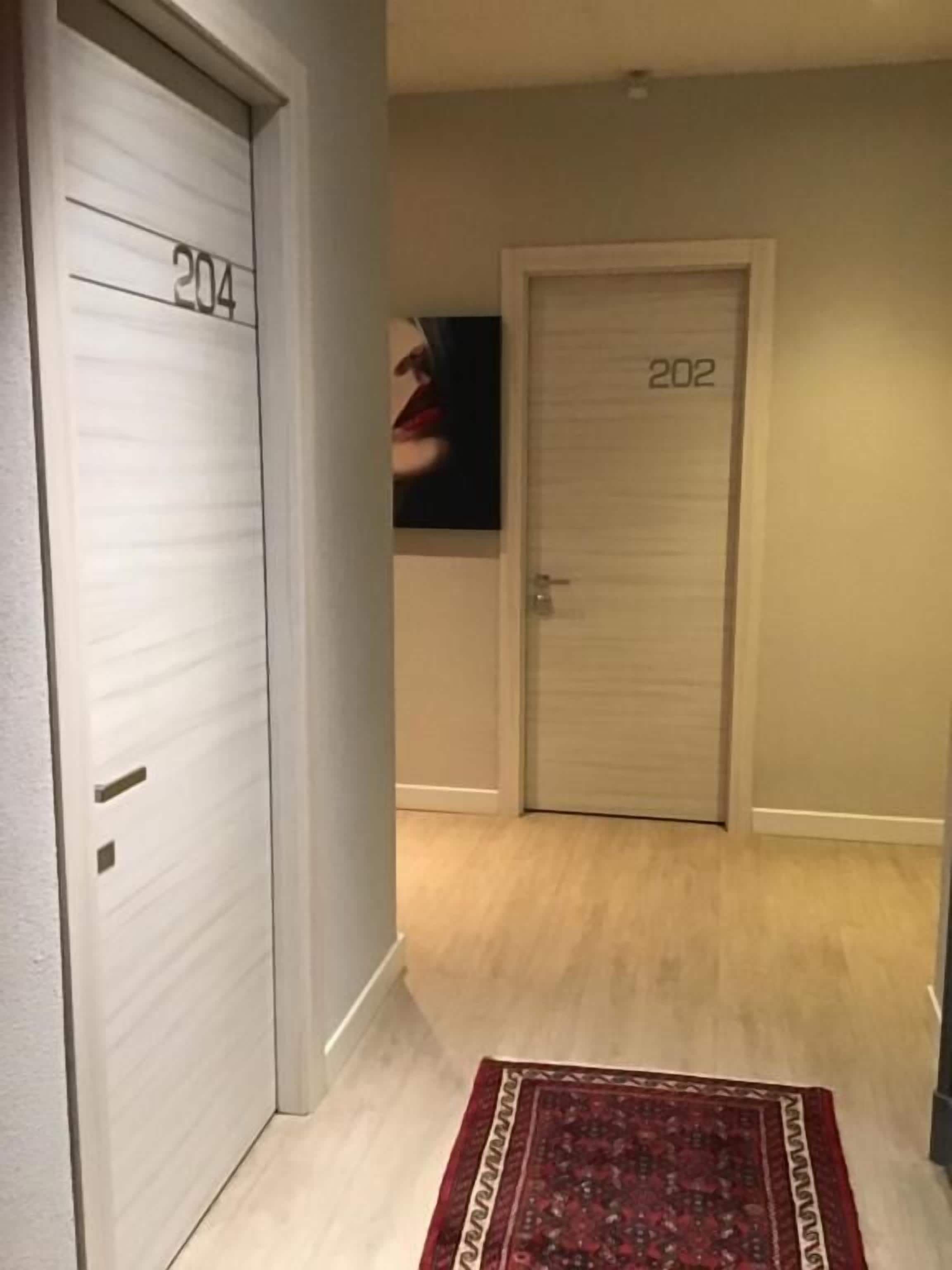 Ein Flur mit zwei Türen, auf denen 204 und 202 stehen, und einem roten, gemusterten Teppich auf dem Boden.