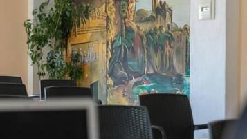 Una habitación con una laptop sobre una mesa, una planta y un mural en la pared.