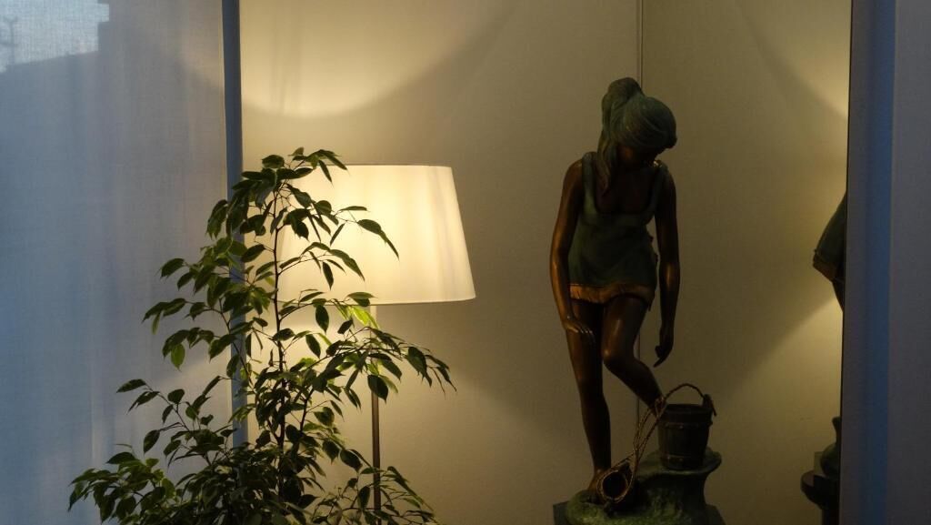 A room with a lamp, a plant, and a statue.