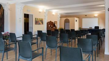 Una sala de conferències amb files de cadires, una pissarra i un piano.