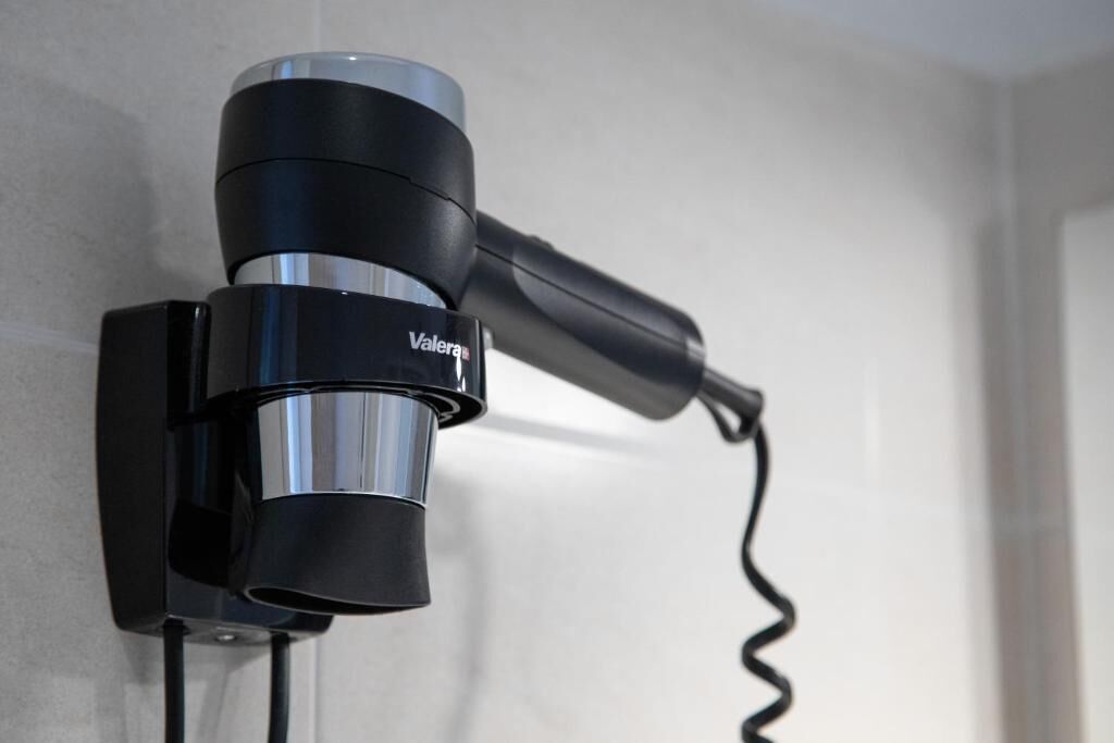 A wall-mounted hair dryer with a cord.