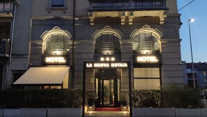A hotel facade with arched windows, a central entrance, and illuminated signage. - Hotel La Nuova Rotaia (Gallarate)