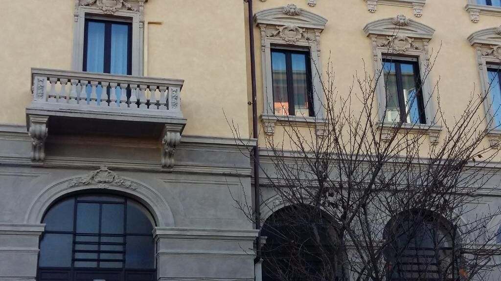 A building facade with arched windows, a balcony with balustrade, and decorative moldings.