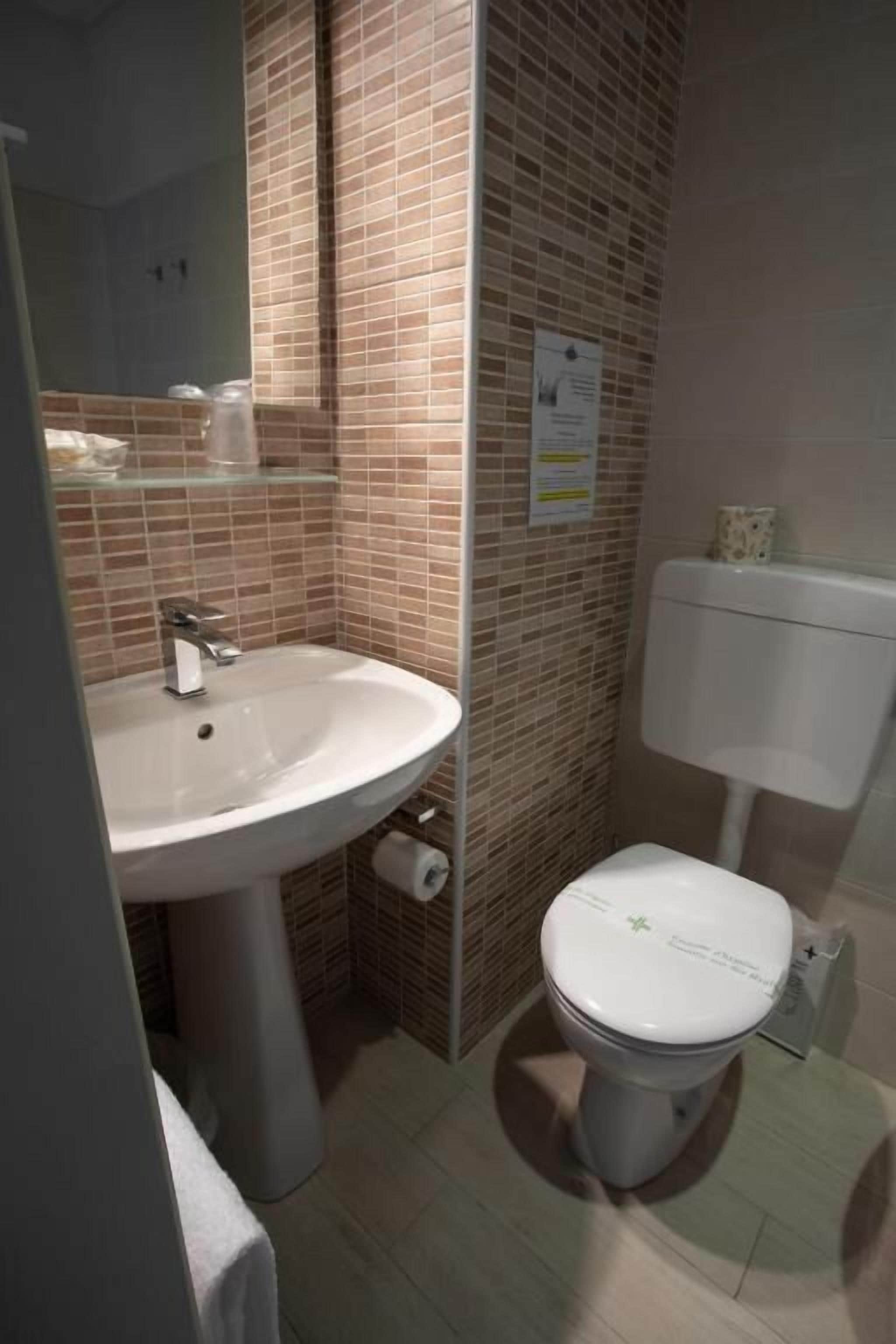 A bathroom with a sink, toilet, and a mirror.