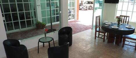 A dining area with a round table, chairs, and a ceiling fan. There is a window with a view of parked cars outside.