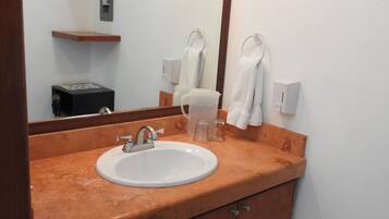 A bathroom with a sink, mirror, towel rack, and a trash bin.