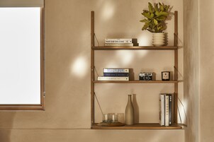A bookshelf with books, a camera, a vase, and a plant.