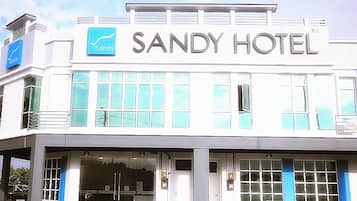 Welcome to the Sandy Hotel, featuring a modern architectural style with a flat facade and large windows.