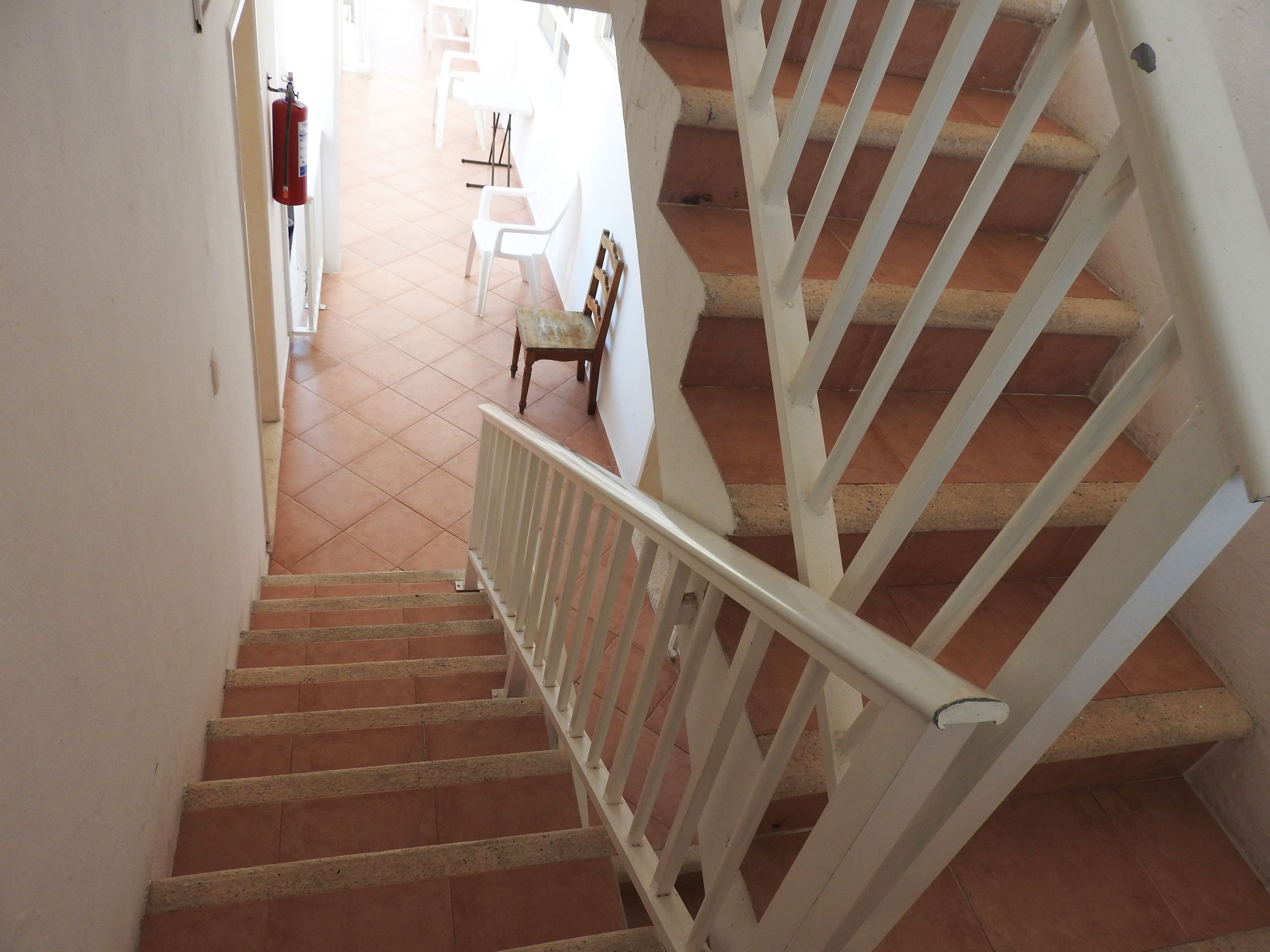 A staircase with white railings and terracotta tiles.
