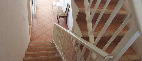 A staircase with white railings and terracotta tiles.