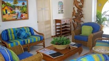 Relax in a cozy living room with a vibrant sofa, armchair, and decorative fish sculpture, perfect for unwinding with a good book.