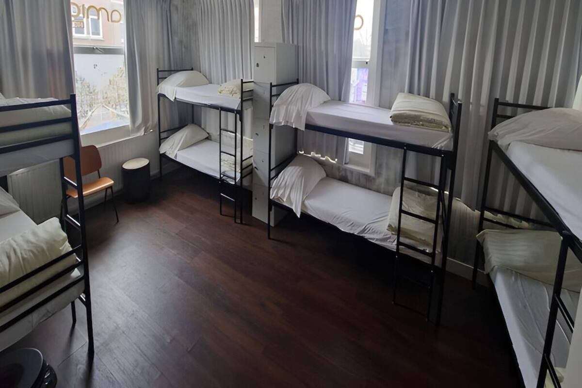Um quarto em dormitório com beliches, uma mesinha e uma cadeira.